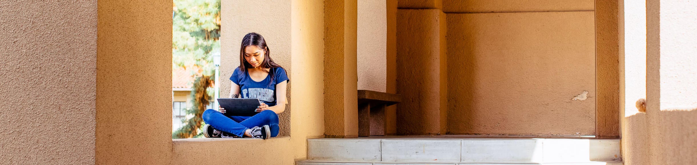 A female student sits in an alcove, reading. 